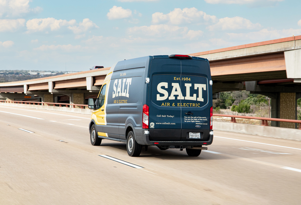 Salt Air & Electric service van driving on a Texas highway with company logo and contact information visible on the back