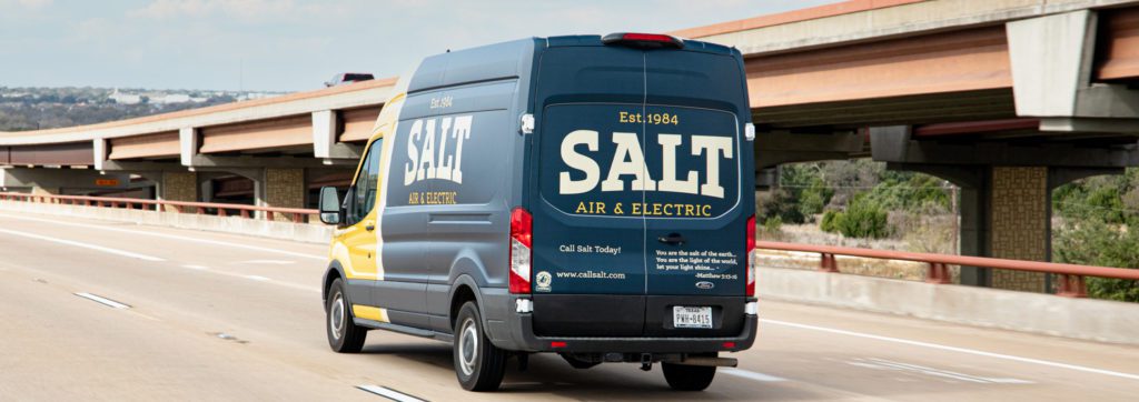 Salt Air & Electric service van driving on the highway with company name and contact details visible on the back