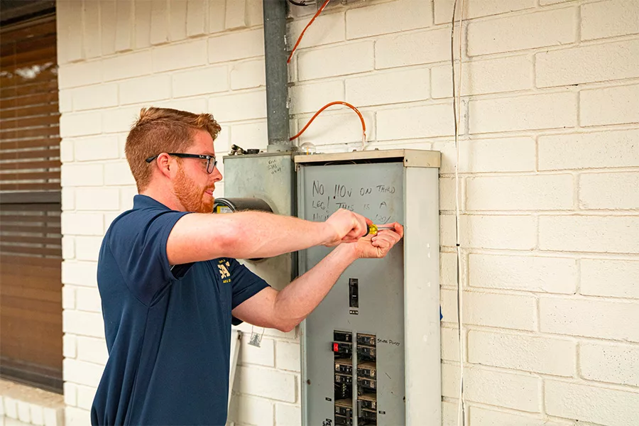 Salt Air & Electric electrician using a screwdriver to work on a residential electrical breaker panel