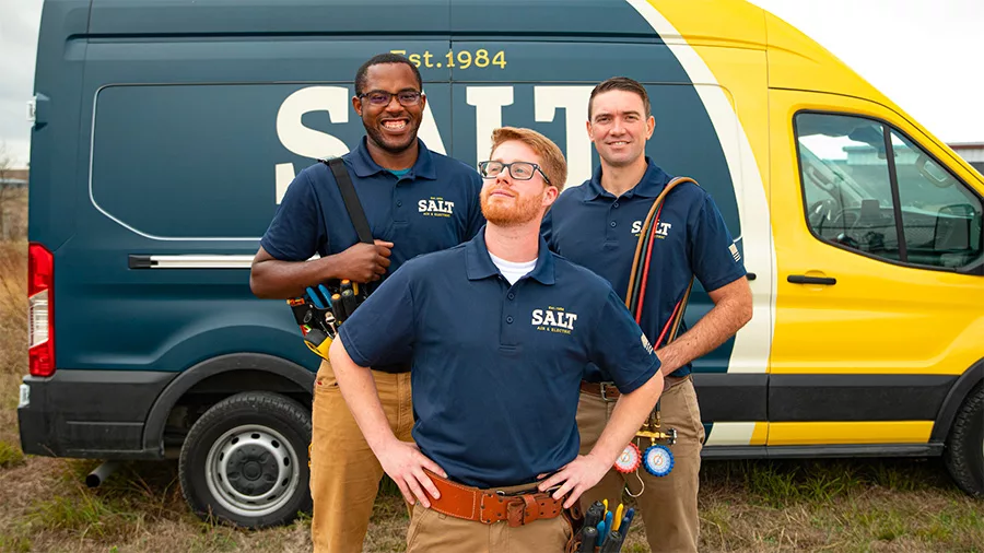 Three Salt Air & Electric technicians in uniform standing confidently in front of a company van