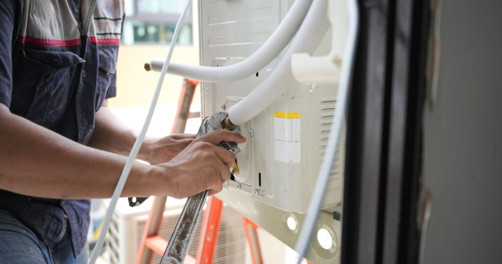Technician tightening connections while installing or servicing an air conditioning unit outdoors