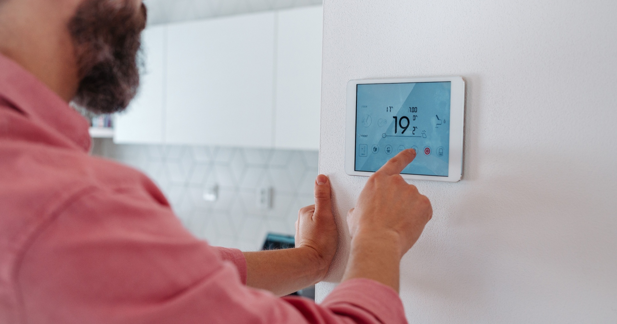 A man adjusting his home's thermostat settings.
