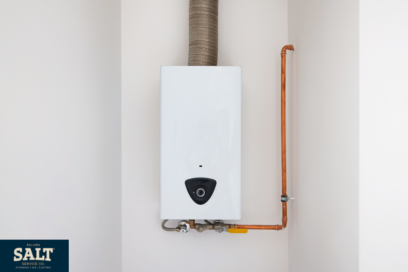 Wall-mounted electric tankless water heater installed inside a residential utility space.